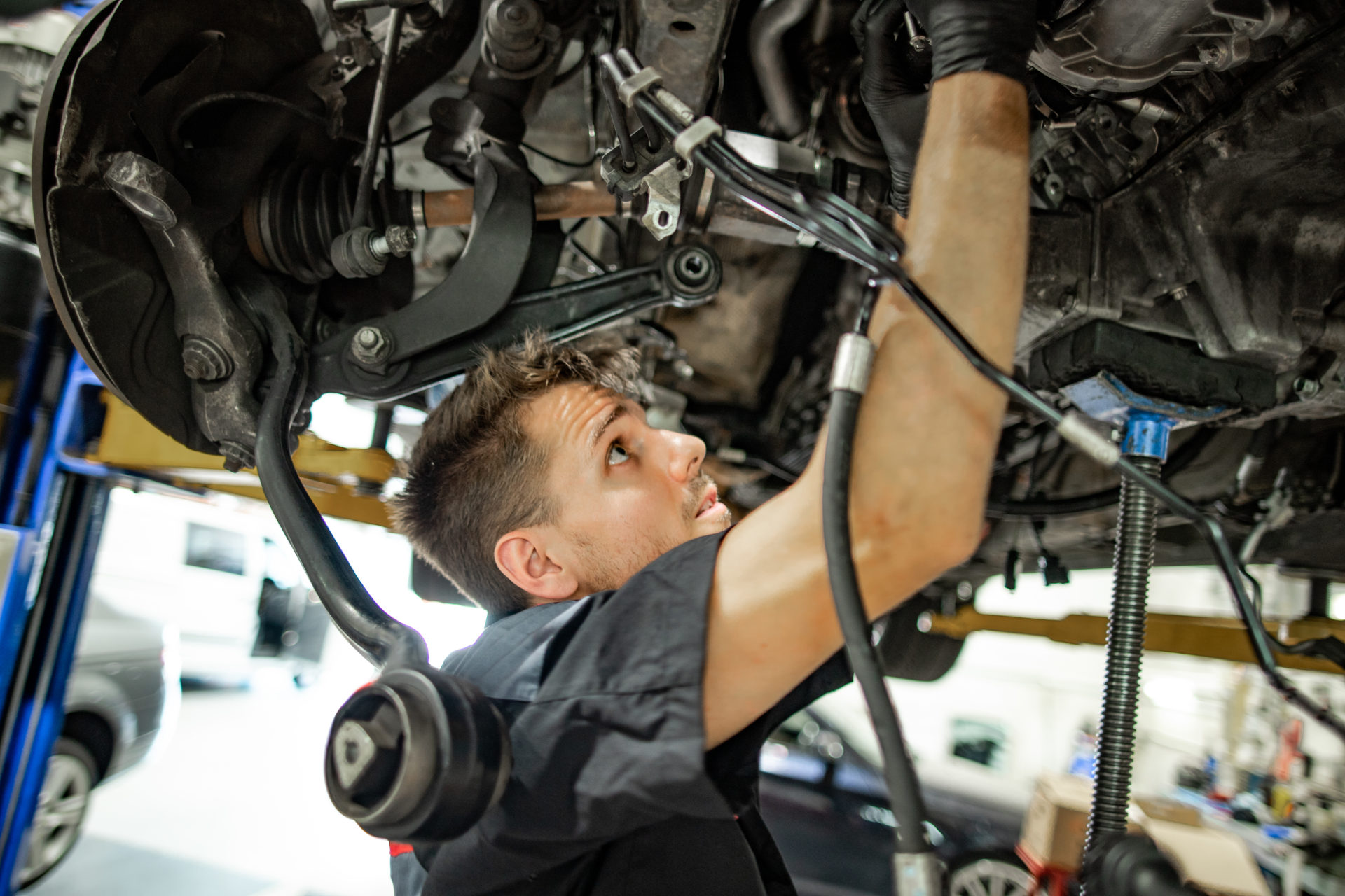 A mechanic underneath a car performing a car inspection.