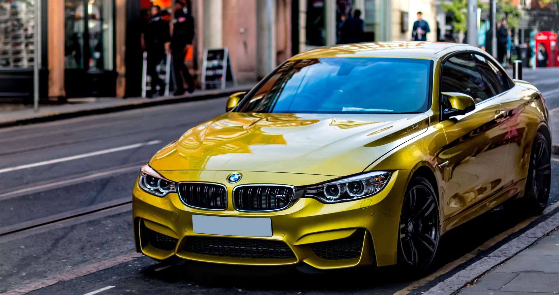 A yellow BMW M4 is parked on a city street.