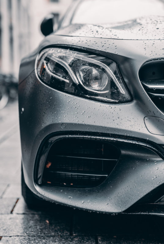 Mercedes-Benz showcasing front grille and headlights during rainy weather.