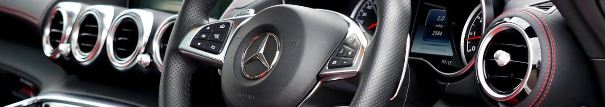 Close-up view of a Mercedes-Benz car interior, showcasing the steering wheel, dashboard, and air vents with metallic and leather finishes—perfectly maintained through expert Mercedes-Benz Servicing.