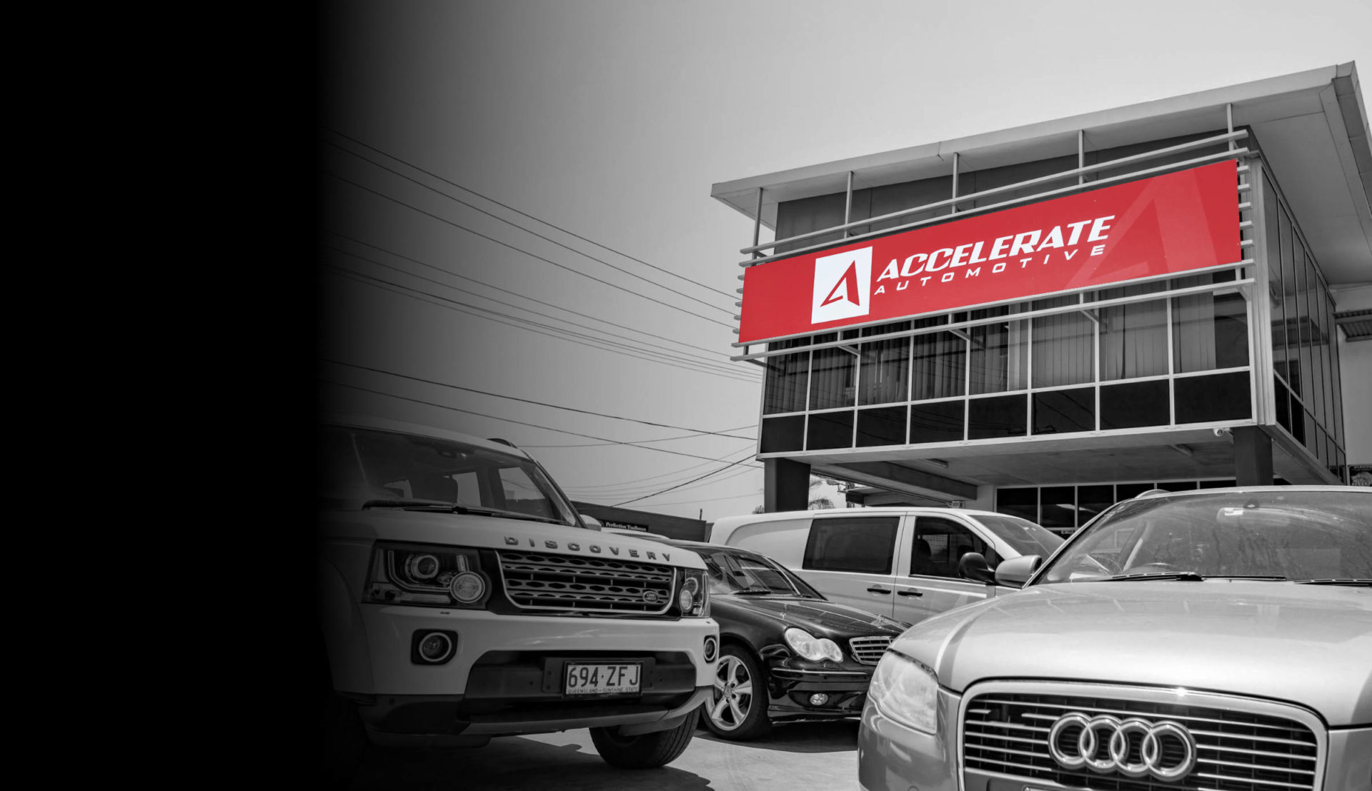 A black and white photo of European cars parked in front of Accelerate Automotive building.