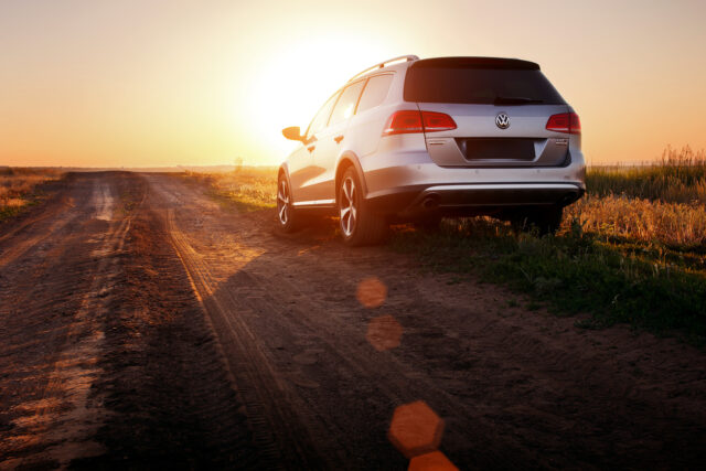 A silver Volkswagen SUV, perfect for long road trips, is parked on a dirt road at sunset in Australia, with sunlight casting long shadows across the scene.